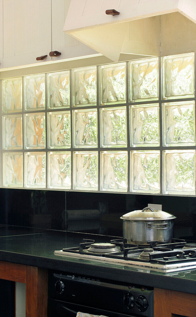 Kochtopf aus Metall auf einem Kochfeld unter Glasbausteinfenstern