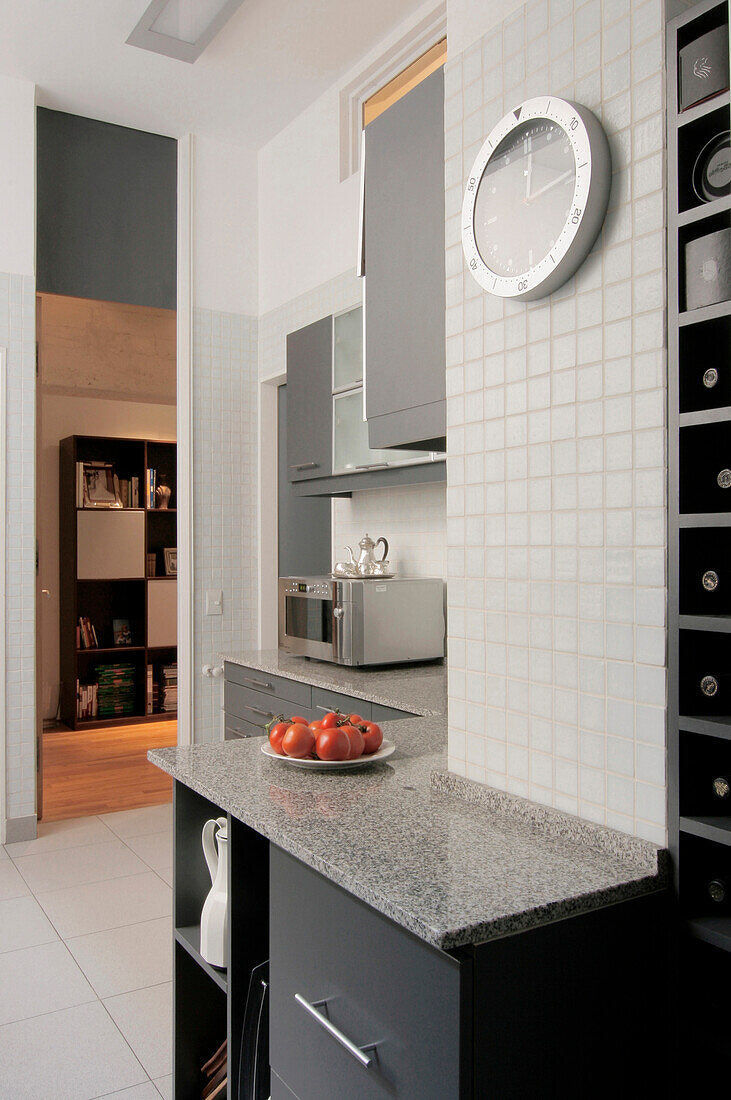 Marble worktop with microwave and wine rack below kitchen clock