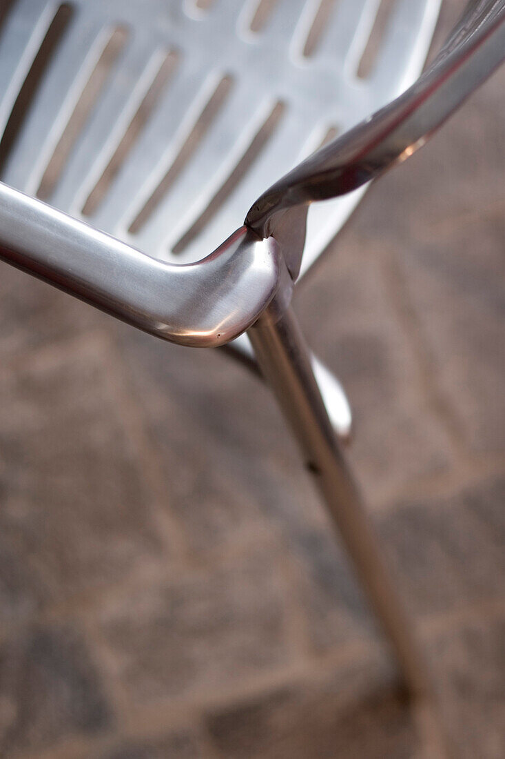 Armlehne und Sitzfläche eines polierten Metallstuhls