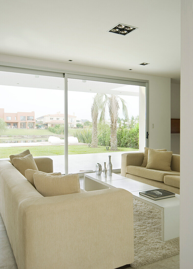 Cream sofas in living room with large glass sliding doors
