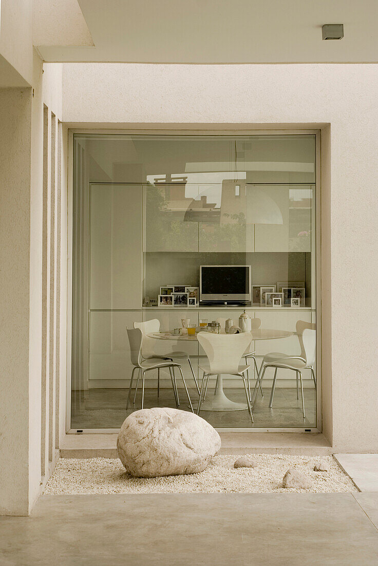 Boulder in courtyard with view through large glass window to kitchen
