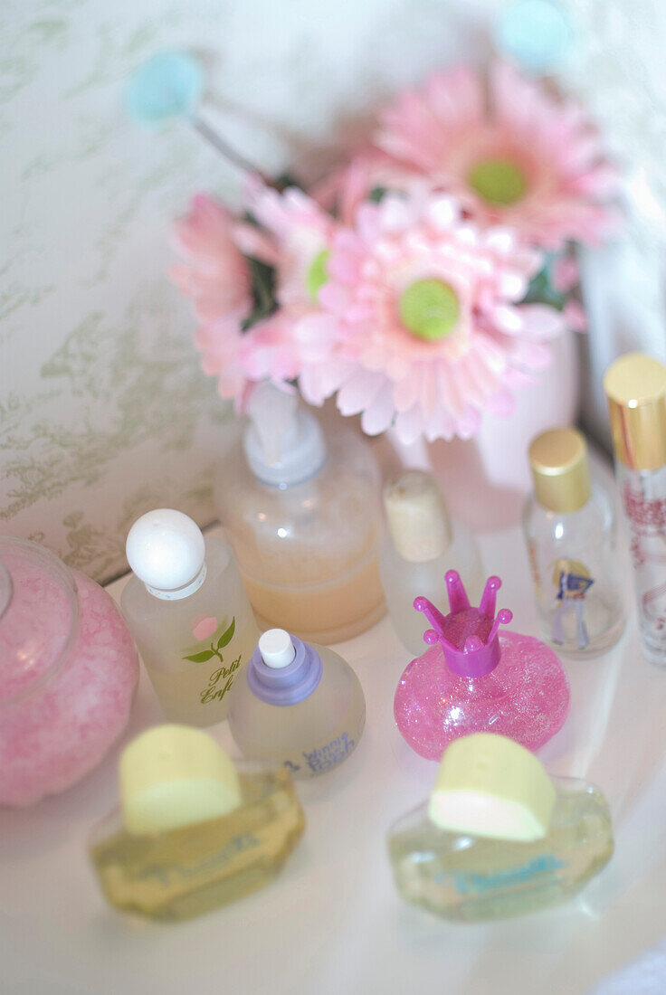 Parfümflaschen und Schnittblumen in Rosa