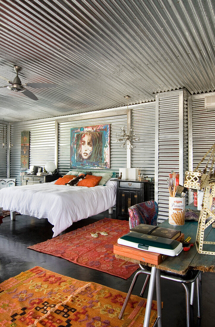 Schlafzimmer mit verzinktem Metall, chinesischen Möbeln und gewebten Teppichen