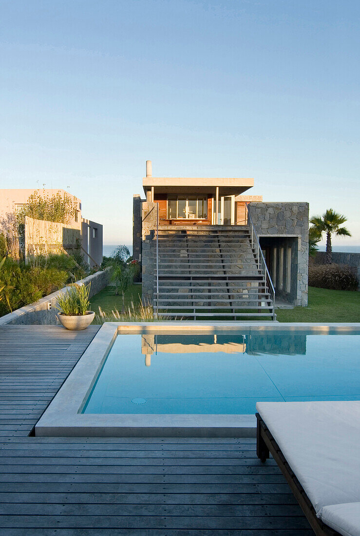 Stone beach house exterior and still water surface of pool