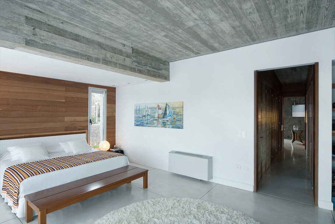 Panelled bedroom with concrete ceiling and striped throw