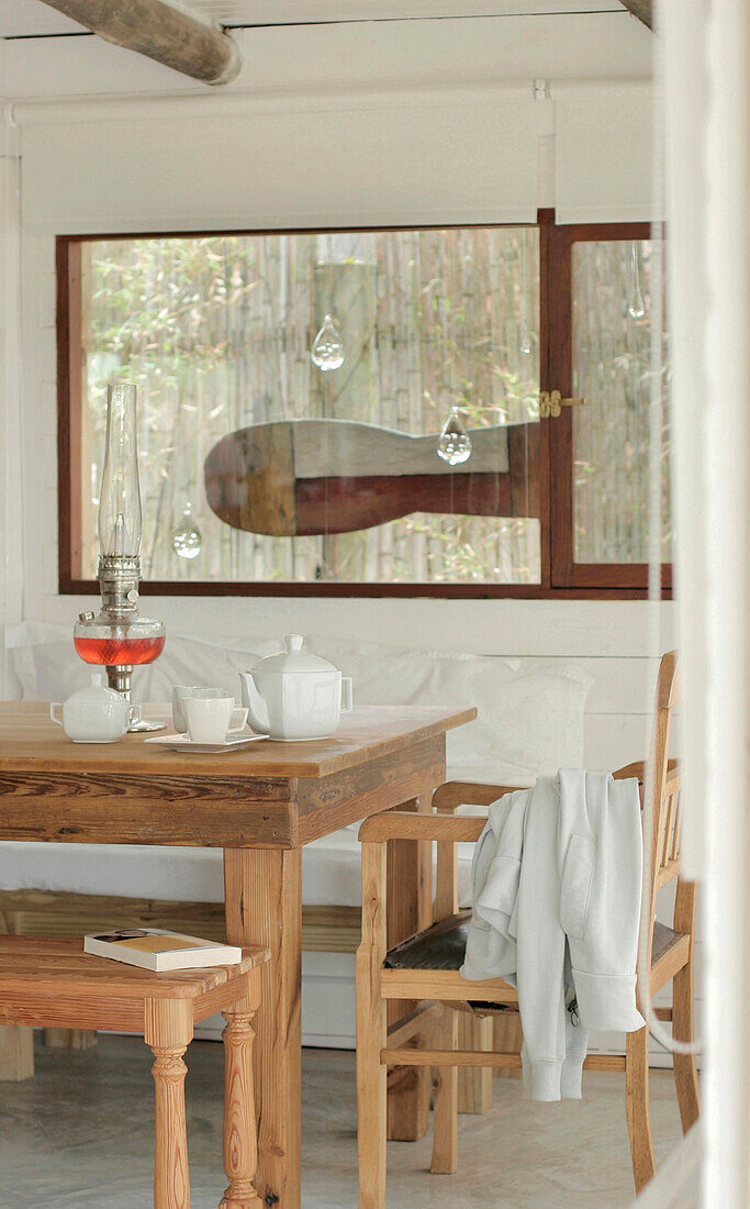 Teeservice auf Holztisch mit Bänken unter dem Fenster