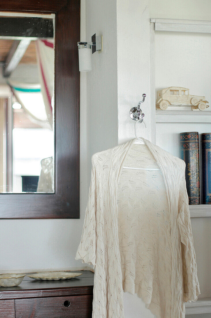Lace cardigan hangs between bedroom mirror and shelves