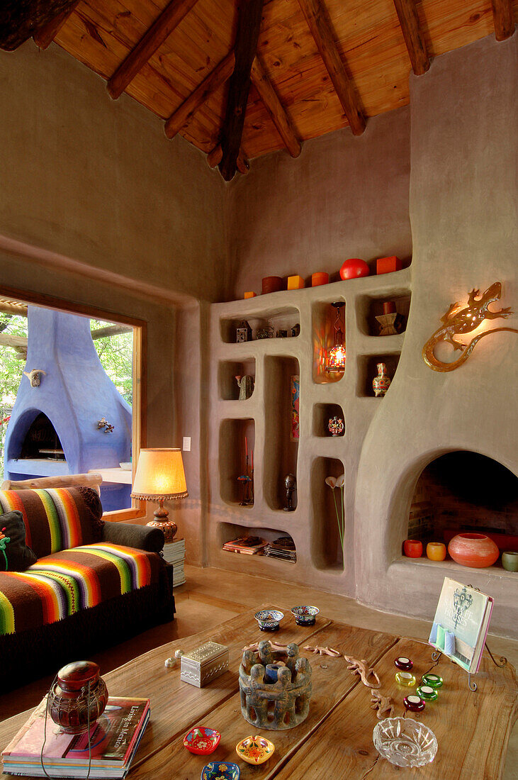 Wohnzimmertisch mit Ornamenten auf Eichenbrettern und Nischenregal aus Beton mit Kamin, der an einen alten Lehmofen erinnert