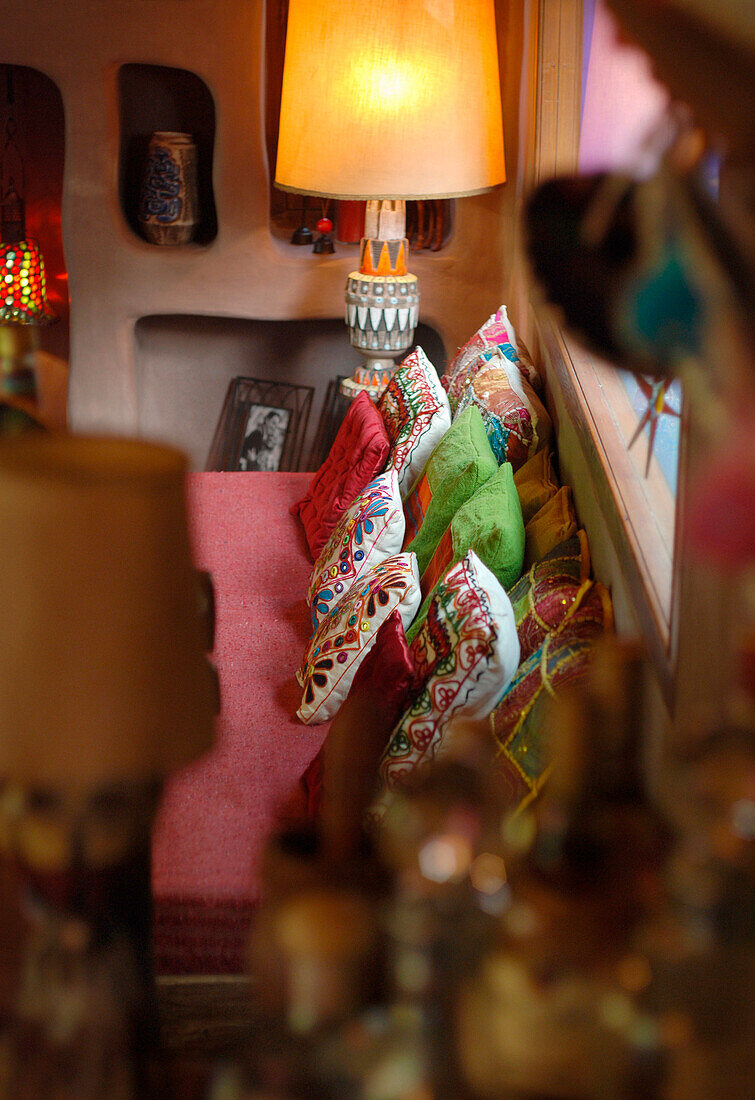 Wohnzimmersofa mit Kissen in verschiedenen Farben und Texturen, Nischenregal aus Beton und Lampe