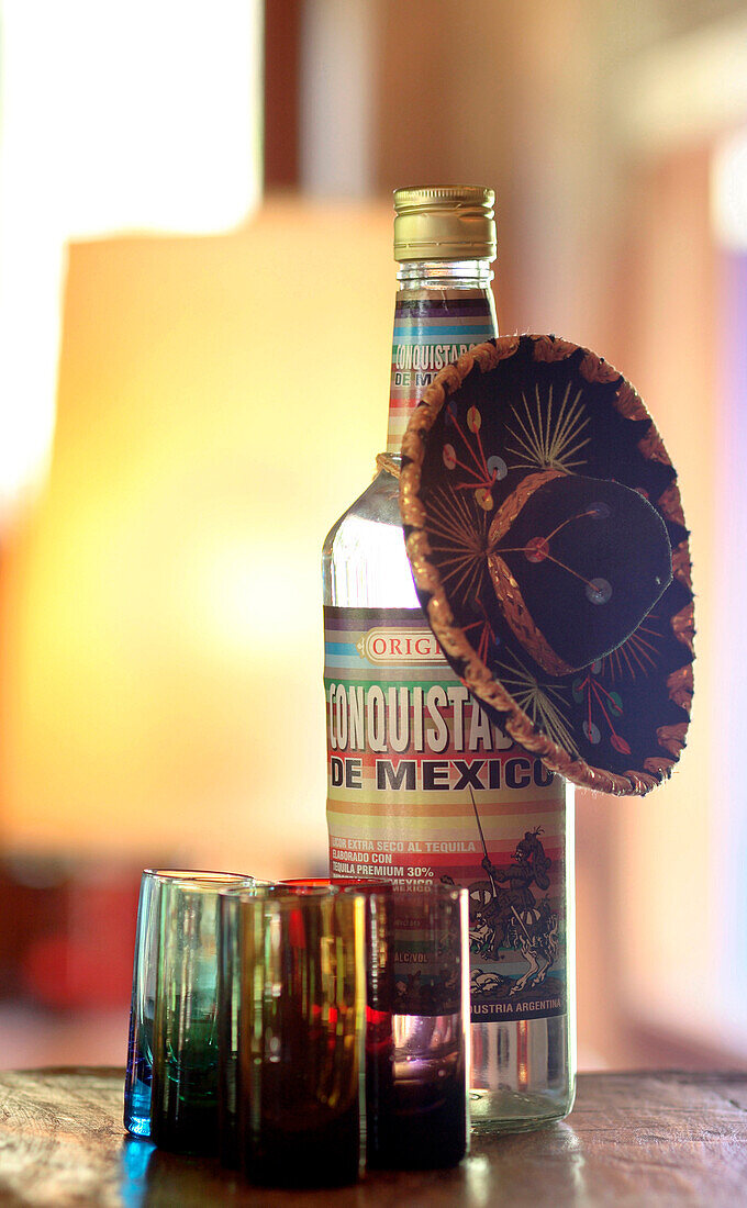 Flasche Tequila-Gläser und mexikanischer Hut auf einem Bar-Tresen aus recycelter Eiche