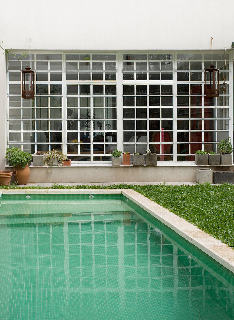Großes weißes Fenster mit Blick auf den Swimmingpool in einem Garten mit Rasen