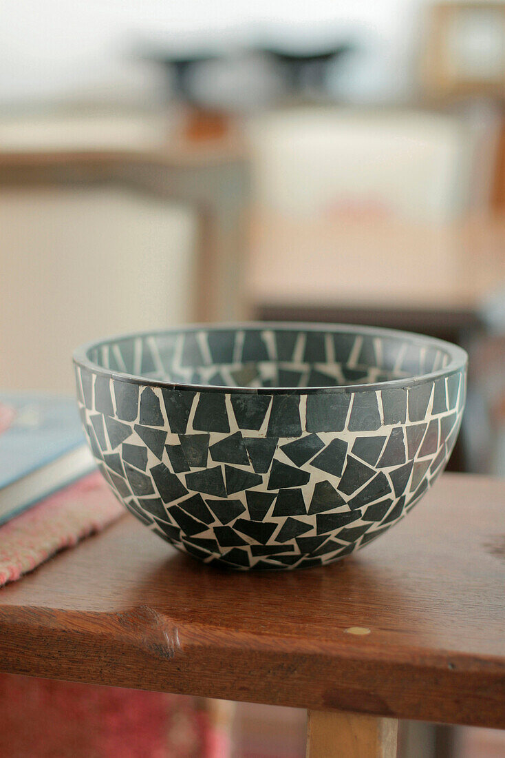 Green ceramic mosaic bowl on wooden shelf