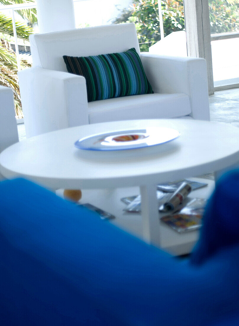 White armchair with striped green cushion and circular coffee table