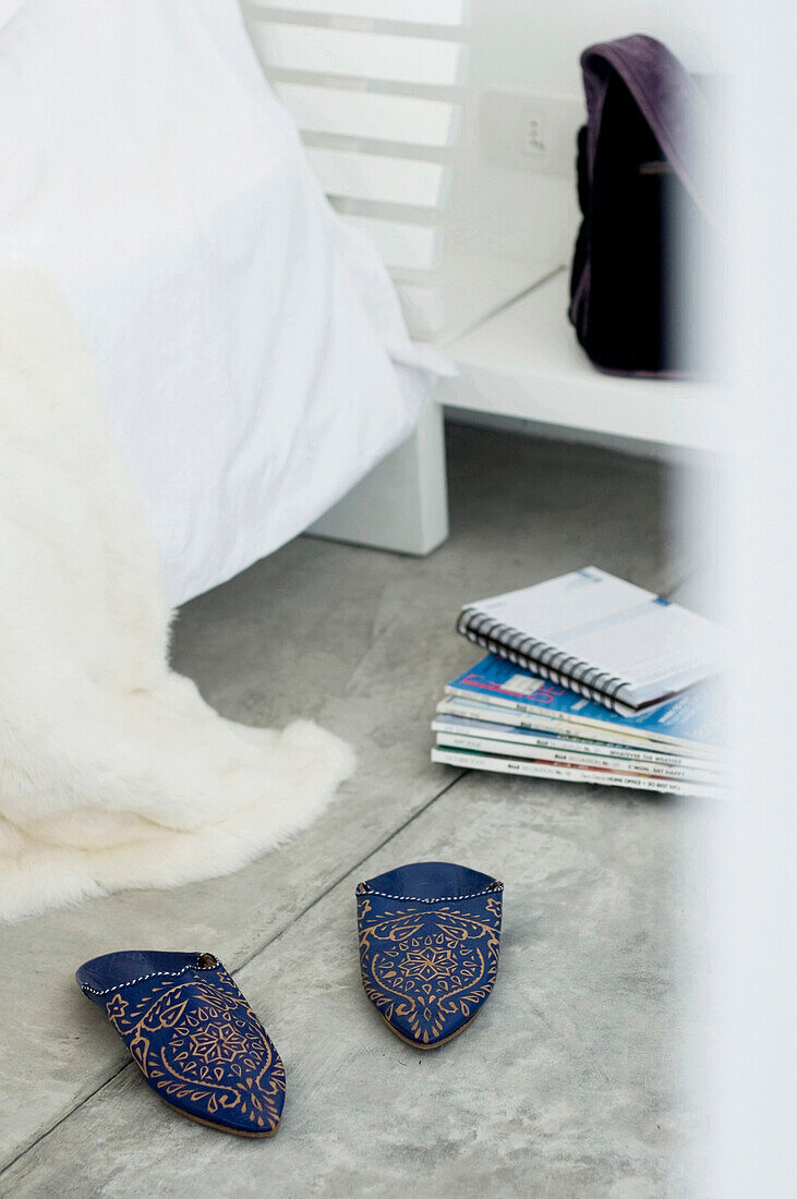 Ornate Indian slippers and notebook on stack of magazines