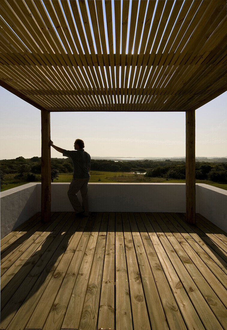 Man leans on rooftop pergola at dusk