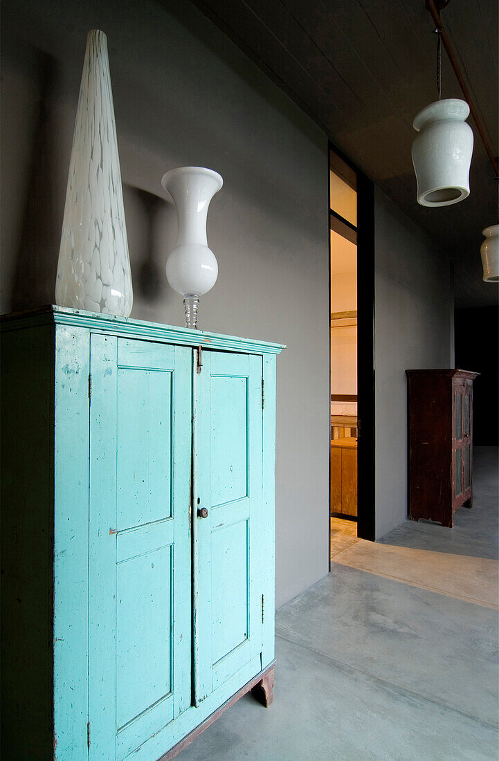 Glass vase on salvaged turquoise hallway cupboard