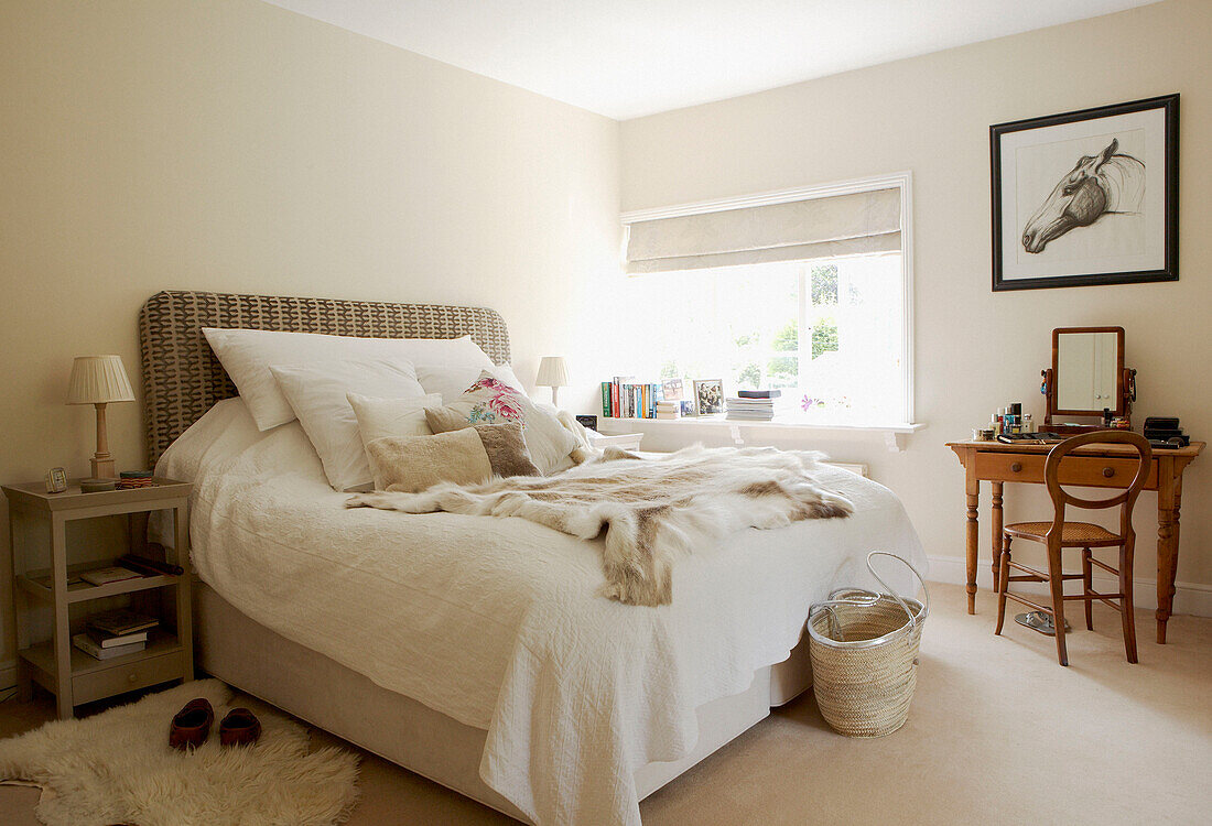 Doppelbett mit weißer Tagesdecke und Felldecke mit Teppich in einem Schlafzimmer in Oxfordshire aus dem 17. Jh.