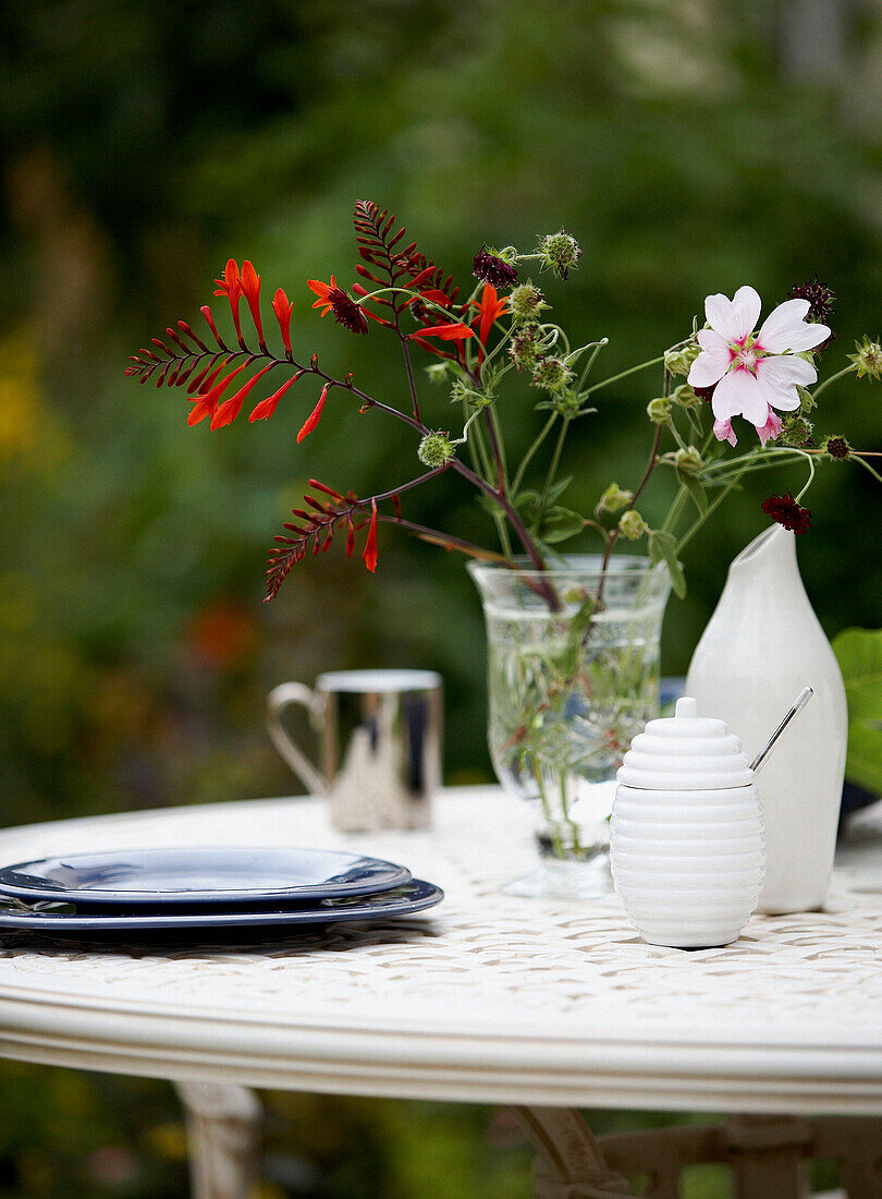 Vase of flowers and plates on garden table