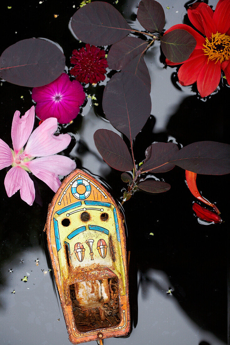 Spielzeugboot Blumen und Blätter schwimmen auf der Wasseroberfläche