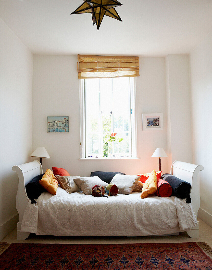 Scatter cushions on daybed below sunlit window
