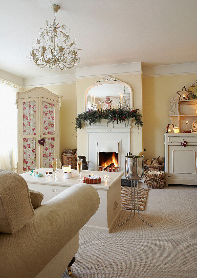 Weihnachtsgirlande über offenem Kamin in weißem Landhaus-Wohnzimmer