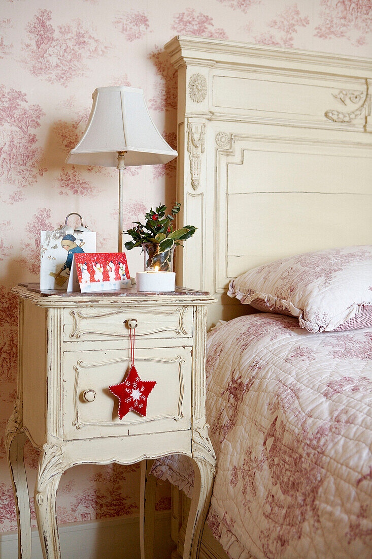 Rosa geblümte Bettdecke und cremefarbener Nachttisch