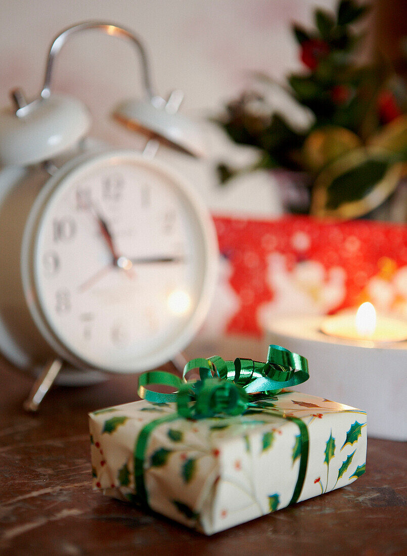 Eingepacktes Weihnachtsgeschenk und weißer Wecker