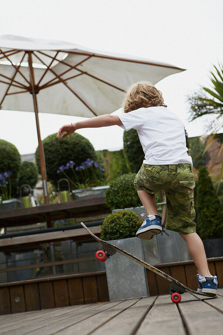Junge spielt auf einem Skateboard im Garten