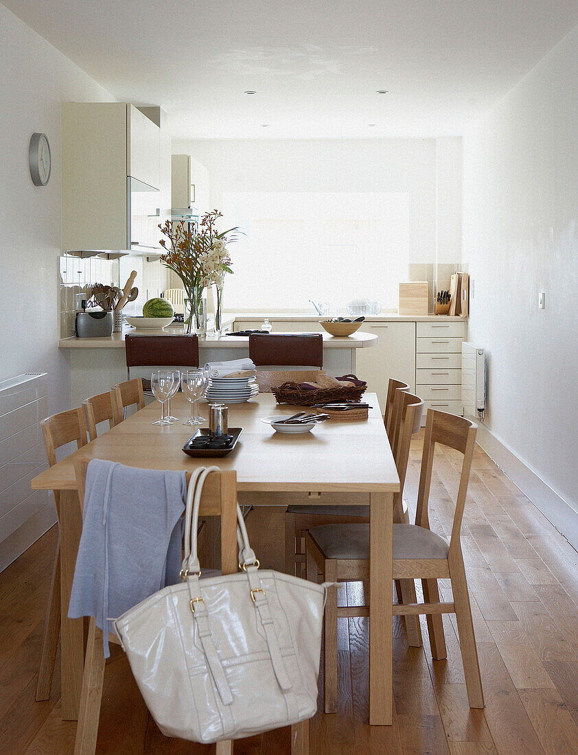 Helle Holzmöbel in einer weißen, sonnenbeschienenen Küche