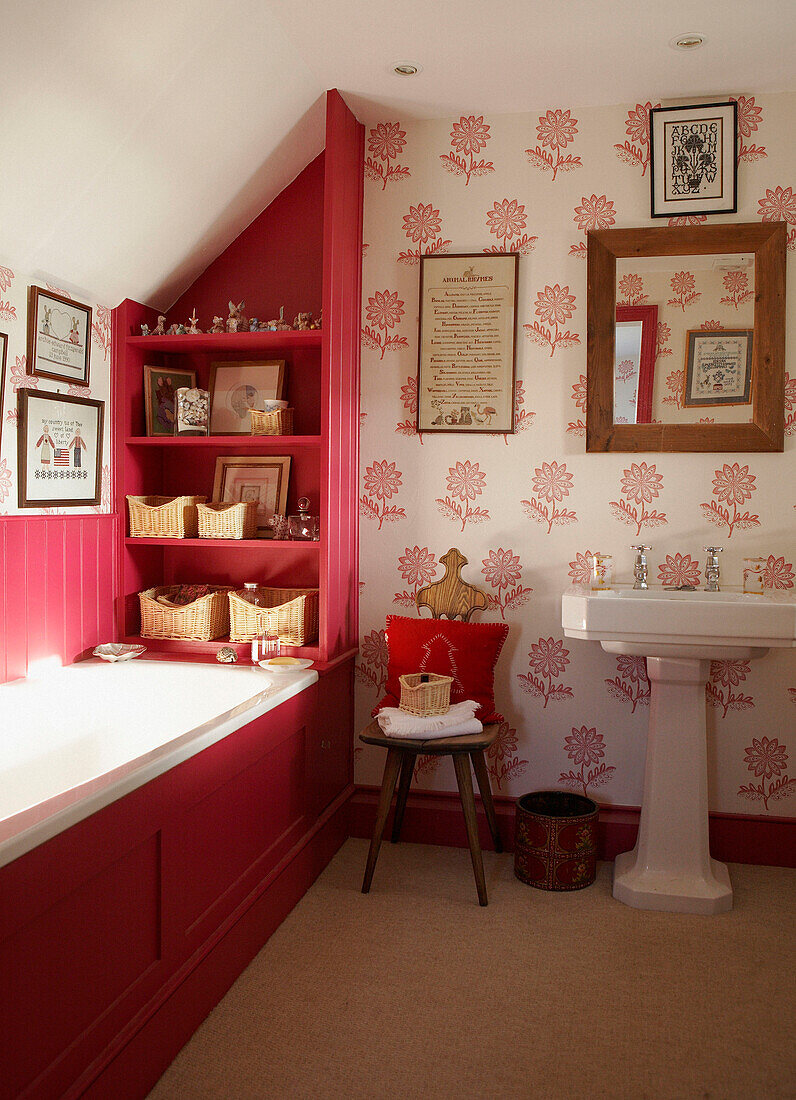 Getäfelte rote Badewanne in einem Badezimmer mit Blumentapete und freistehendem Waschbecken