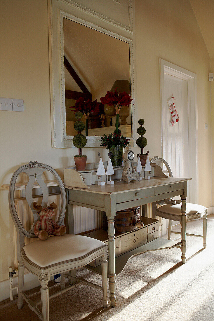 Painted console table under square mirror in white interior with Christmas decorations