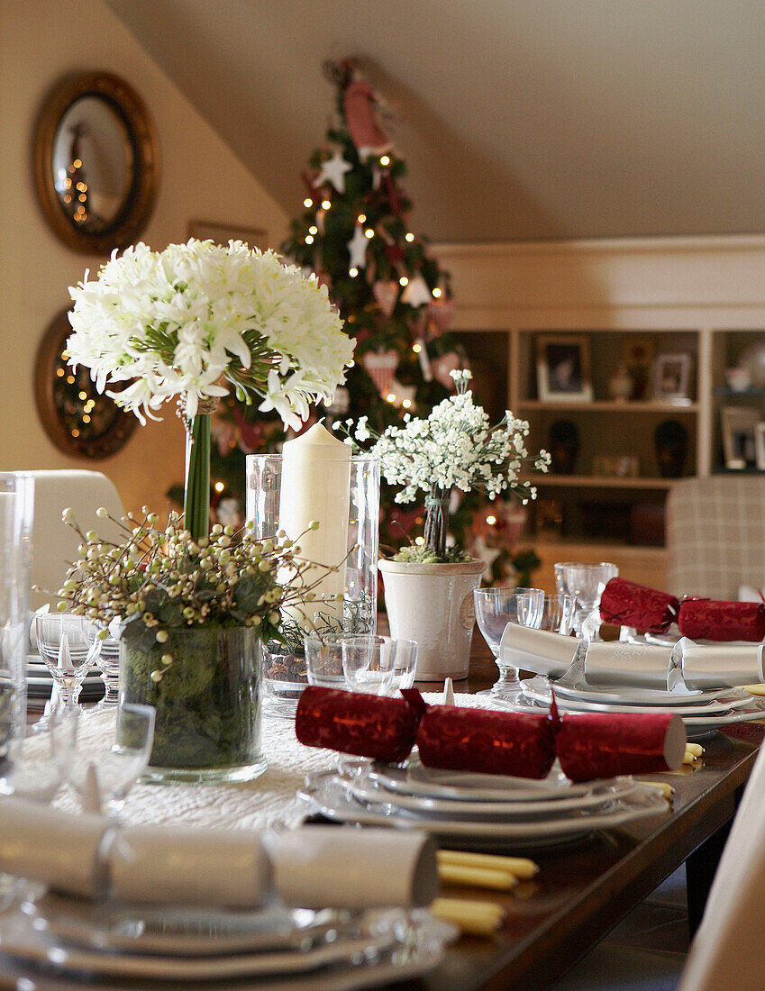 Blumenarrangement und Cracker auf dem für das Weihnachtsessen gedeckten Tisch