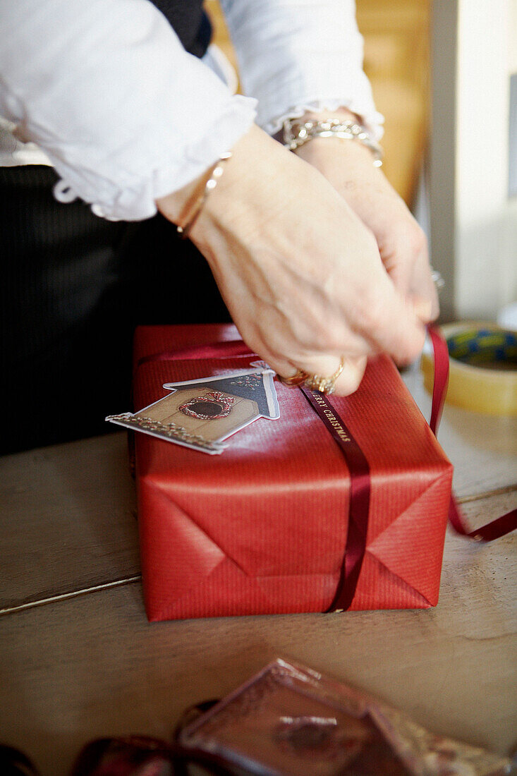 Frau verpackt Weihnachtsgeschenke mit Schleifenband