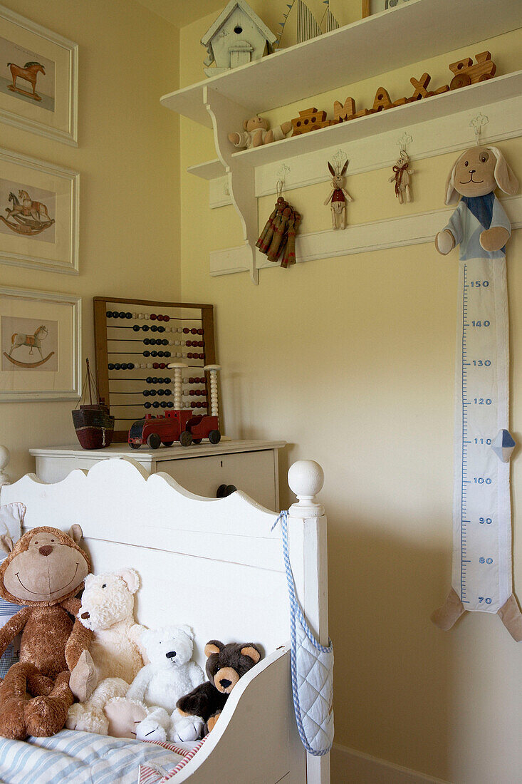 Gemaltes Einzelbett in einem Kinderzimmer mit Kuscheltieren und Abakus