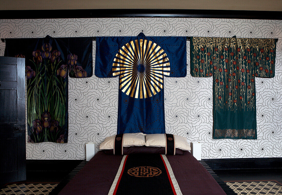 Kimonos displayed against patterned wallpaper of Georgian farmhouse bedroom