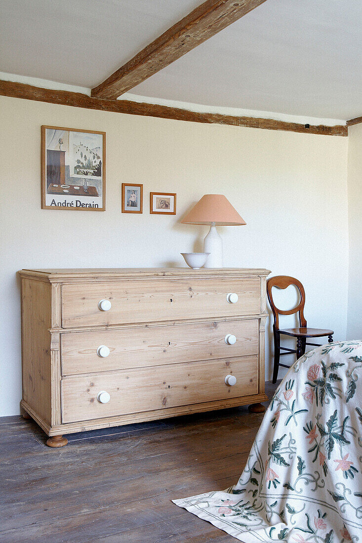Kommode aus Naturholz in einem Schlafzimmer mit Balken im Landhausstil