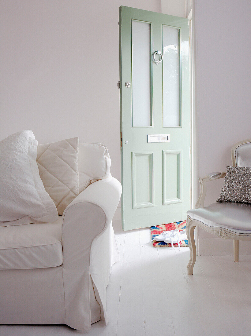 Light green open front door with white sofa in entrance room