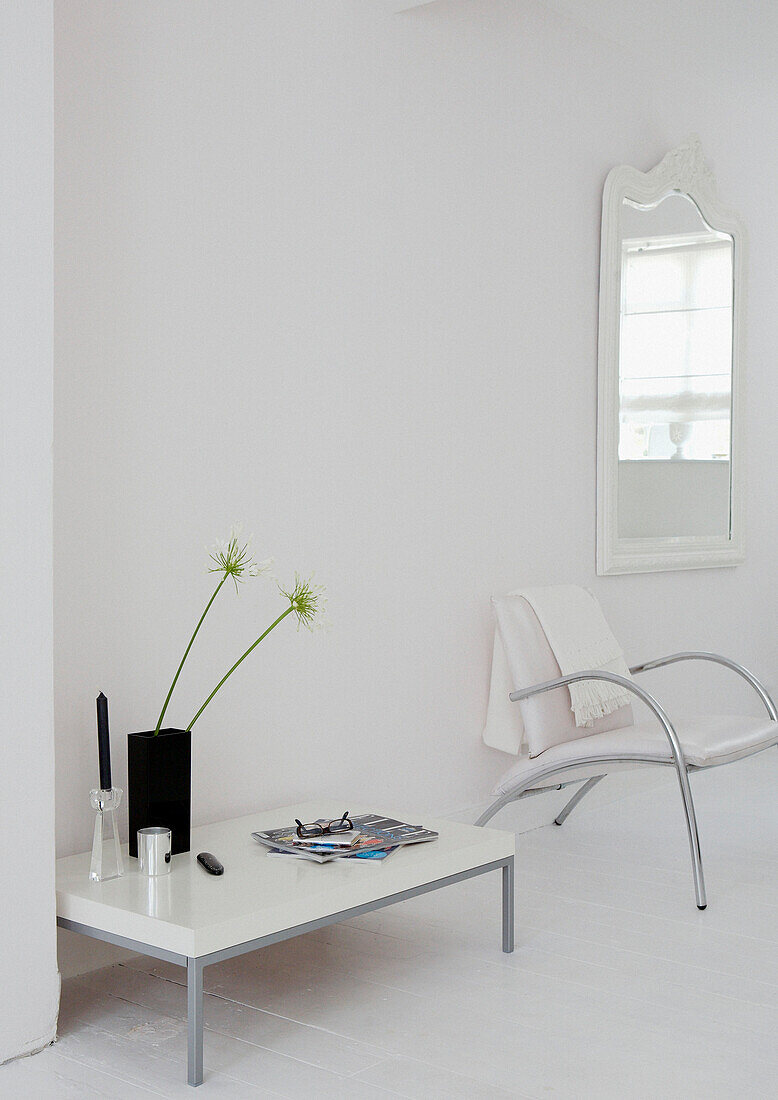 Sessel mit Metallrahmen und niedriger Beistelltisch mit Spiegel in einem ganz in Weiß gehaltenen Eingangsraum