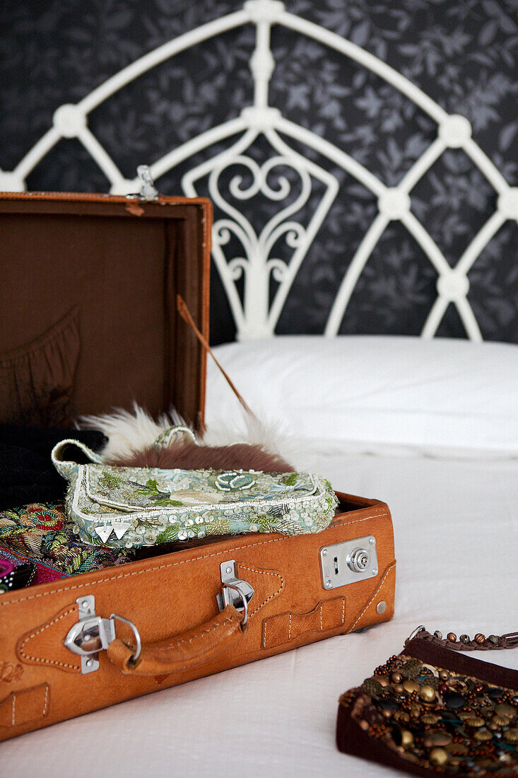 Perlenhandtaschen in offenem Koffer auf weißem Gusseisenbett