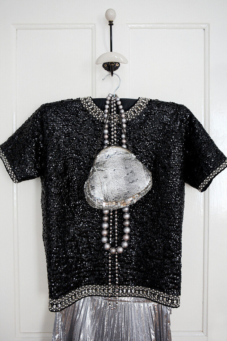 Schwarzer Perlenaufsatz und silberne Handtasche hängen an der Rückseite der Schlafzimmertür