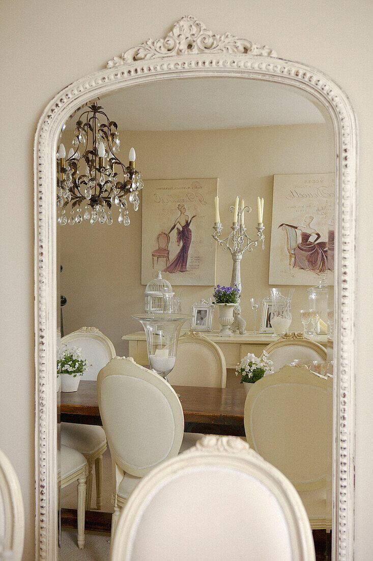Dining room with crystal drop chandelier reflected in mirror with painted frame
