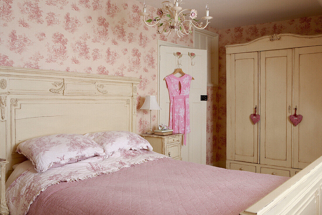 Painted bed and wardrobe in room with co-ordinating wallpaper and bed linen