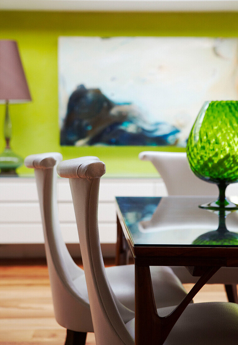 Dining room chairs with green glass vase on glass topped table