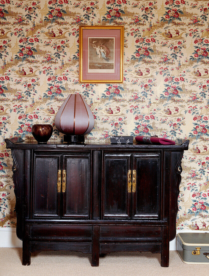 Japanese lacquered antique cabinet set against patterned wallpaper in Georgian townhouse 