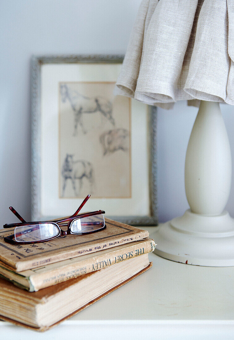 Reading glasses and books on bedside table