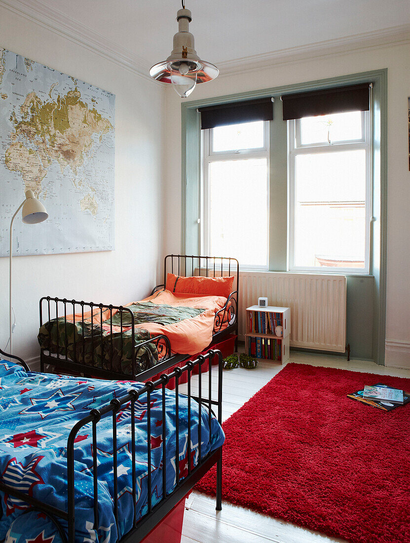 Metallgerüstete Betten mit kontrastierenden Bettdecken und Teppich in einem Schlafzimmer in einem edwardianischen Reihenhaus