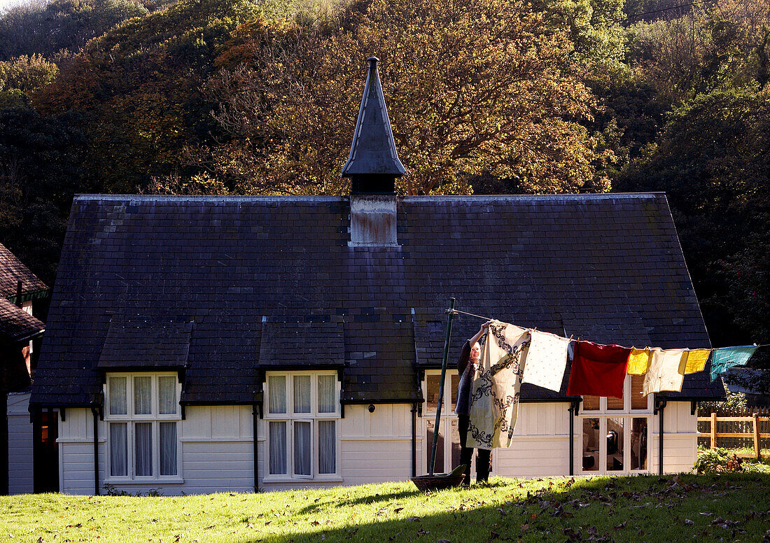 Frau hängt Wäsche auf Gras mit Kirchturmgebäude auf