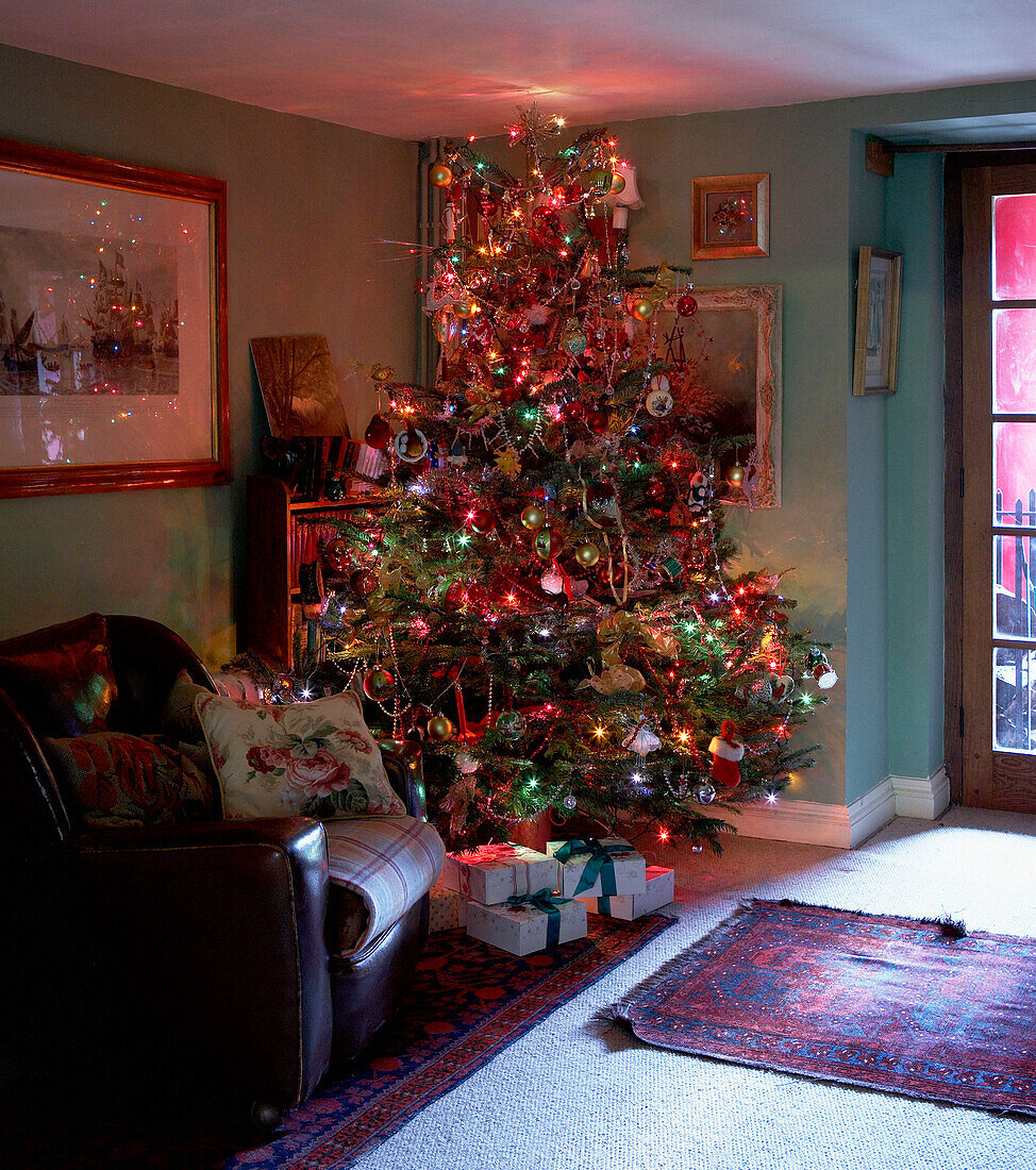 Weihnachtsbaum und Sessel im Wohnzimmer eines walisischen Bauernhauses aus dem 16. Jh.