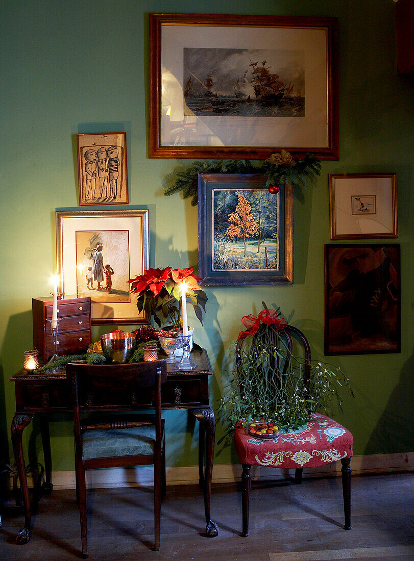 Art displayed on green wall with desk and chairs in 16th Century Welsh farmhouse