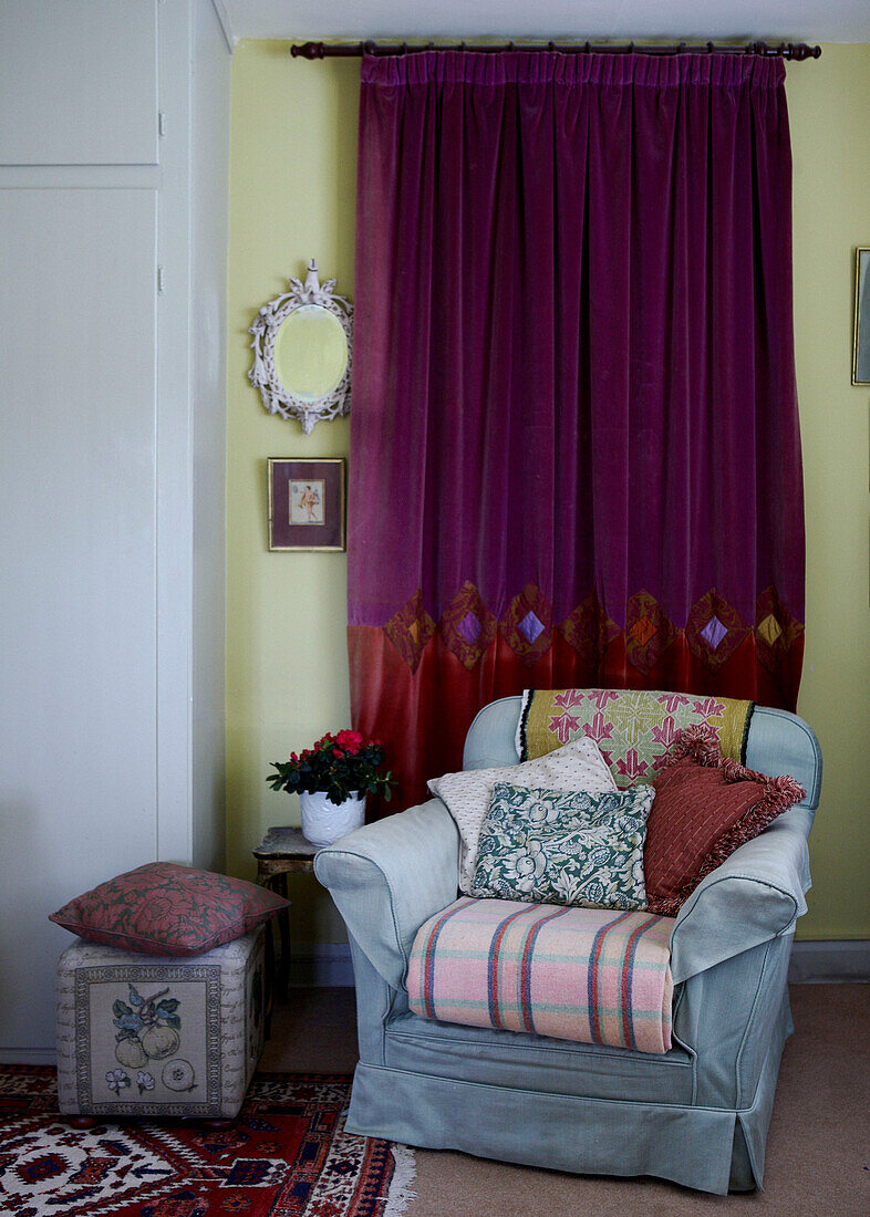 Upholstered armchair and bright pink fuscia curtains in 16th Century farmhouse bedroom